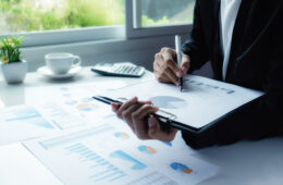 Asian business woman analyzing investment charts on desk. Vintage tone Retro filter effect,soft focus,low light.(selective focus).