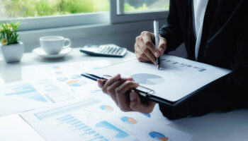 Asian business woman analyzing investment charts on desk. Vintage tone Retro filter effect,soft focus,low light.(selective focus).