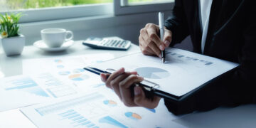 Asian business woman analyzing investment charts on desk. Vintage tone Retro filter effect,soft focus,low light.(selective focus).